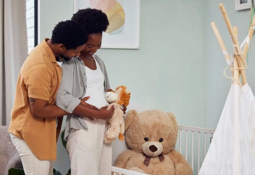 Love, teddy bear and pregnant couple in the nursery with excitement while preparing for their baby. Happy, pregnancy and young African man with his maternal wife looking at toy together in bedroom