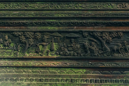 Close up shot of carved stone wall with moss in sacred monkey forest. Balinese architecture carving stone with monkeys scene