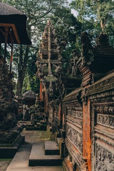 Side view photo of balinese temple architecture in sacred monkey forest. Indonesian stone carved sculpture and walls in monkey sanctuary