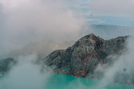 Scenic view of misty mountain and blue lake. Hill landscape and lagoon through the fog