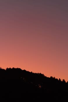 Dark silhouette of hills on pink sunrise view. Sundown landscape with purple color sky