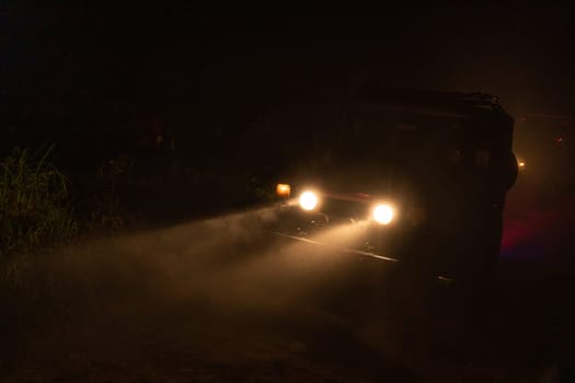 Car with headlights on in the night. Tourism safari travelling car through midnight