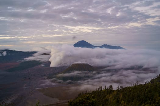 Landscape view of misty mount Bromo volcano. Foggy morning in the java national park with mount Semeru