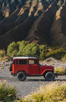 Close up view of red jeep with Bromo volcano background. Travelling vehicle in Semeru national park