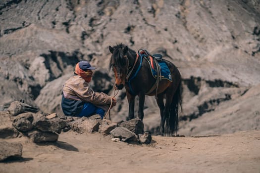 Close up shot of tenggerese horseman waiting for tourists. Horse trip in Bromo Mount volcano
