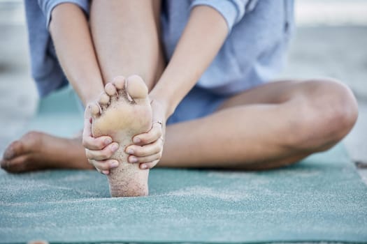 Woman, injury and foot pain from beach yoga, exercise and health. Closeup female massage joint pain of bare feet, muscle and orthopedic accident, problem and podiatry risk from pilates workout at sea.