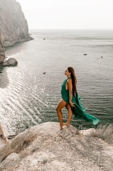 Woman sea green dress. Side view a happy woman with long hair in a long mint dress posing on a beach with calm sea bokeh lights on sunny day. Girl on the nature on blue sky background