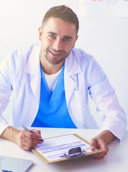 Portrait of a male doctor with laptop sitting at desk in medical office