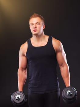 Handsome muscular man working out with dumbbells.