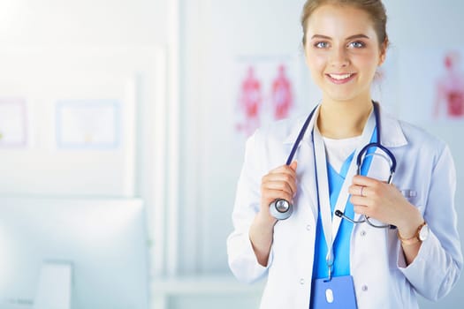 Portrait of young woman doctor with white coat standing in hospital.