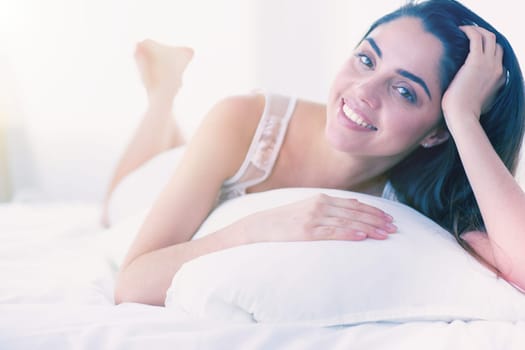 Pretty woman lying down on her bed at home.