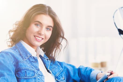 Image of a confident young woman sitting at working desk