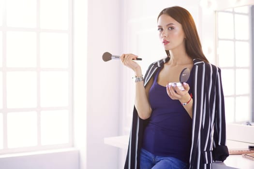 Closeup portrait of woman with makeup brush near face.