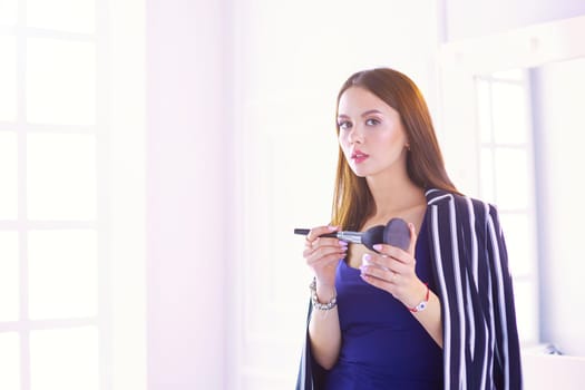 Closeup portrait of woman with makeup brush near face.