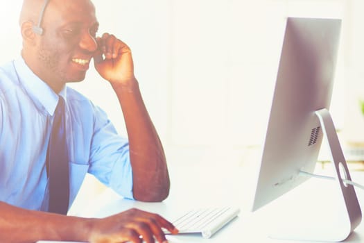 African american businessman on headset working on his laptop.