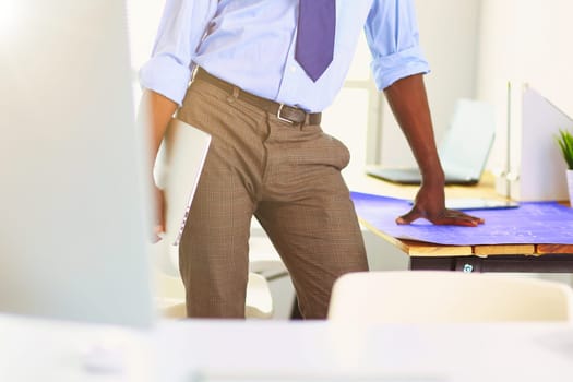 African american architect working with computer and blueprints in office.