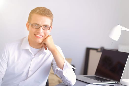 Young businessman working in office, sitting at desk