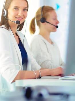 Smiling businesswoman or helpline operator with headset and computer at office.