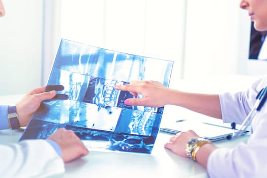 Two doctors studying x-ray image, consulting in bright office.