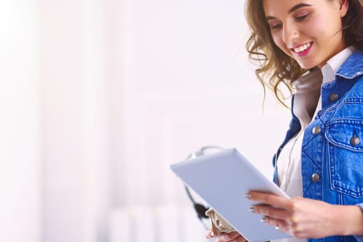 Smiling woman drinking coffee and using tablet in the cafe