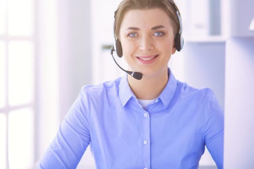 Serious pretty young woman working as support phone operator with headset in office.