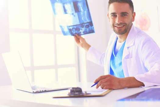 Handsome doctor is talking with young female patient and making notes while sitting in his office