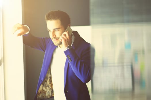 Business man in suit talking on phone and looking away near the window