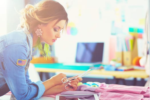 Fashion designer woman working with ipad on her designs in the studio.