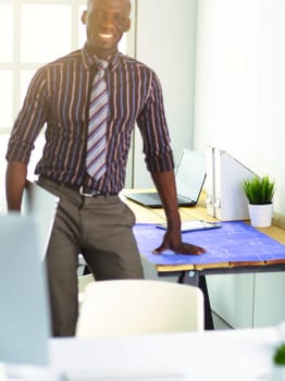 African american architect working with computer and blueprints in office.