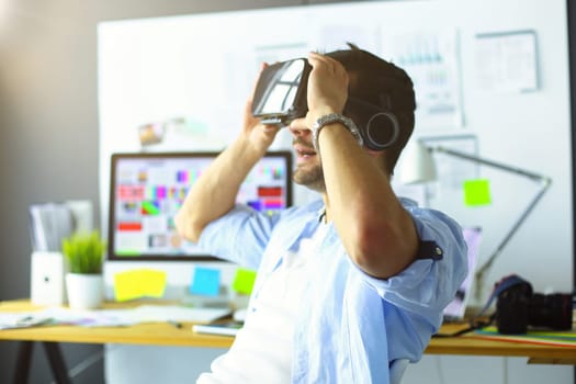 Young male software programmer testing a new app with 3d virtual reality glasses in office