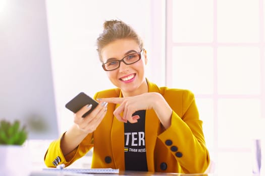 Businesswoman sitting in office with laptop on telephone.