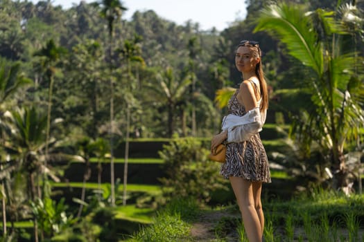 Portrait of beautiful girl with green rice terrace background. Exploring and admiring balinese rice agriculture