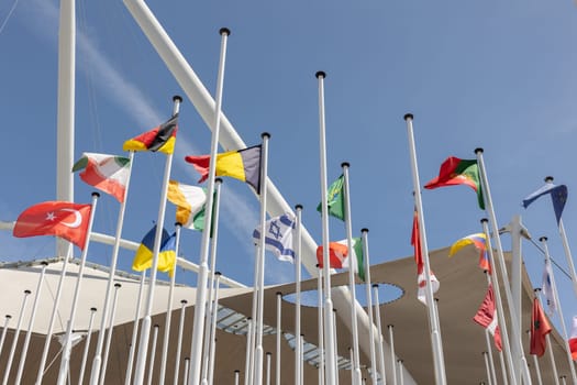 Flags of different countries at the background of blue clear sky. Mid shot
