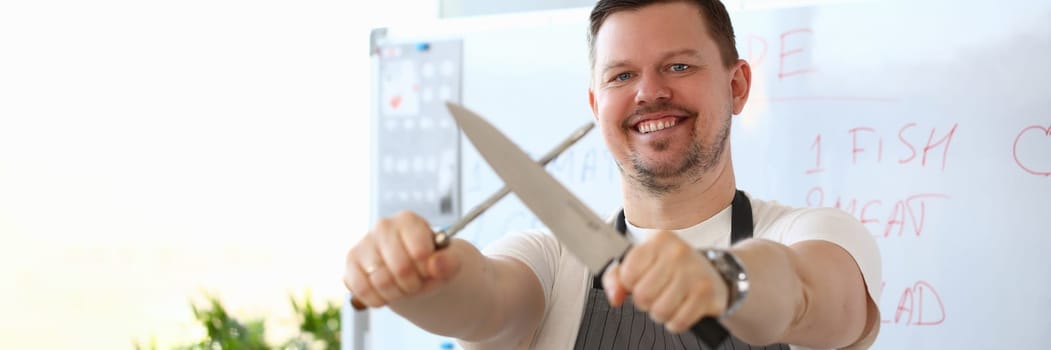 Smiling handsome male cook is holding sharp knife. Chef and culinary education
