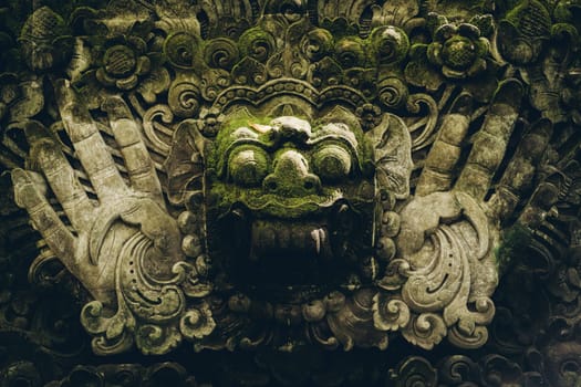 Close up shot of stone face statue in monkey forest. Balinese sculpture architecture in sacred monkey sanctuary