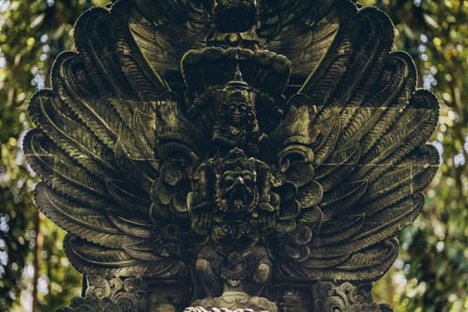 Close up shot of stone sculpture covered with moss in monkey forest. Traditional balinese architecture in ubud sanctuary