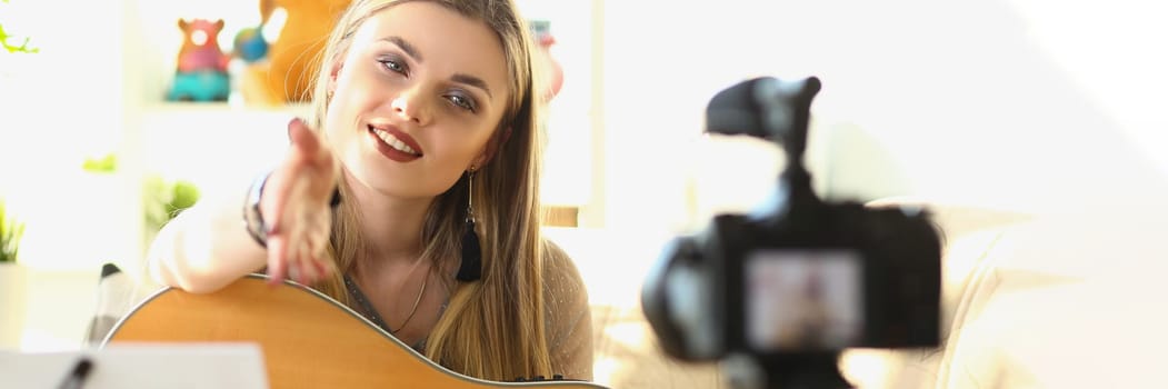 Female musician recording guitar teaching videos. Singing and playing female blogger on guitar in front of camera