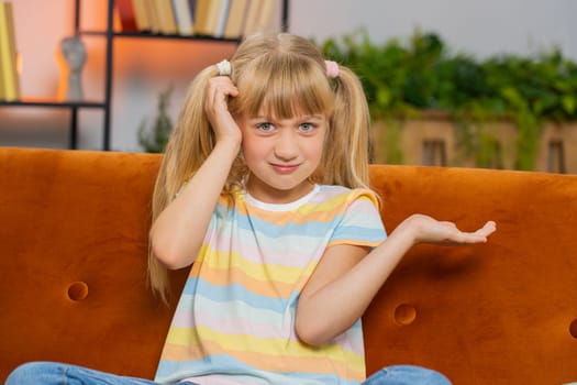 I dont know what to say. Confused Caucasian preteen school girl feeling embarrassed about ambiguous question, having doubts, no idea, being clueless and uncertain. Young blonde child kid at home room