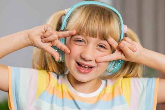 Portrait of happy overjoyed toddler girl kid in wireless headphones relaxing at home room choosing listening favorite energetic disco dancing music. Children weekends leisure activities. Lifestyles