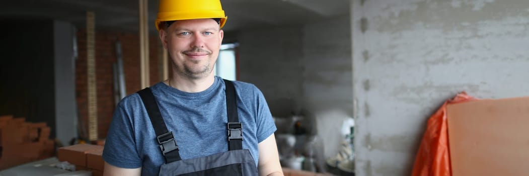 Smiling handsome male builder in hardhat holding pen and clipboard. Construction services and quality control of construction works