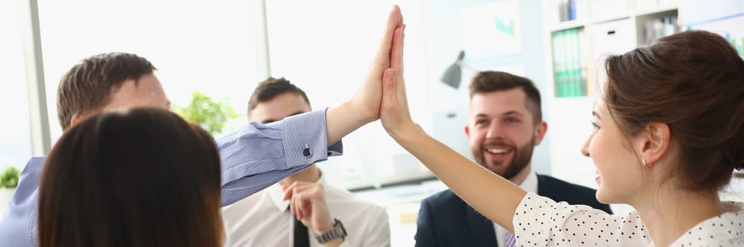 Enthusiastic teammates high-fives celebrate shared accomplishments and corporate success. Business people gathered at group meeting and team building concept