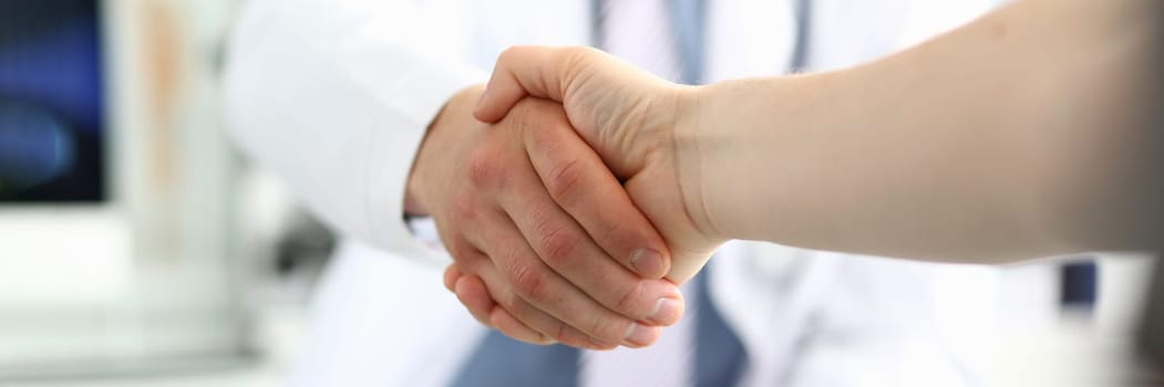 Doctor shaking hands with patient in clinic and thanking handshake for excellent treatment. Trust partnership and health insurance concept