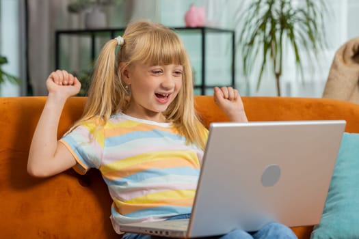 Surprised toddler girl child kid use laptop computer, receive good news message, shocked by sudden victory, celebrate game play win, lottery jackpot, purchases online shopping at home. Lifestyles