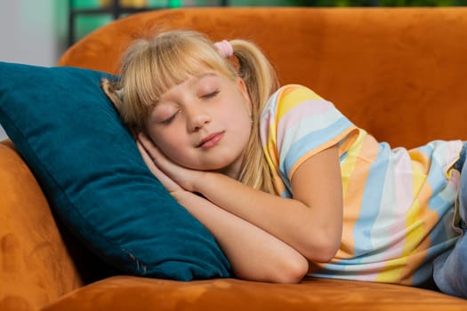Tired preteen school girl lying down in bed taking a rest at home on couch. Carefree blonde child kid napping, falling asleep on comfortable sofa with pillows. Closed her eyes enjoy daytime nap alone