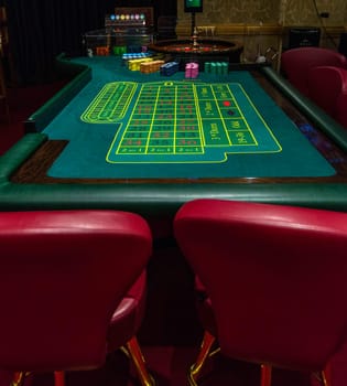 Casino, gambling and entertainment concept - roulette table and stack of poker chips