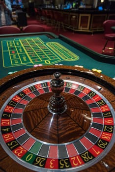 Casino, gambling and entertainment concept - roulette table and stack of poker chips