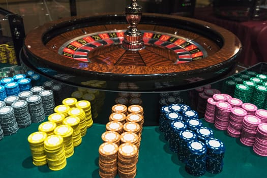 Casino, gambling and entertainment concept - roulette table and stack of poker chips
