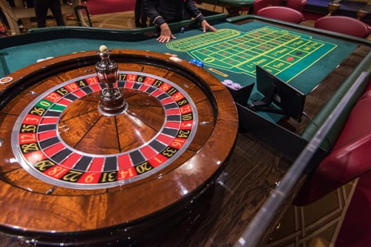 Casino, gambling and entertainment concept - roulette table and stack of poker chips