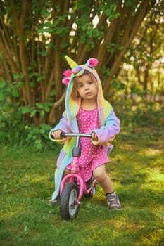 Adorable child riding a bike in the garden.