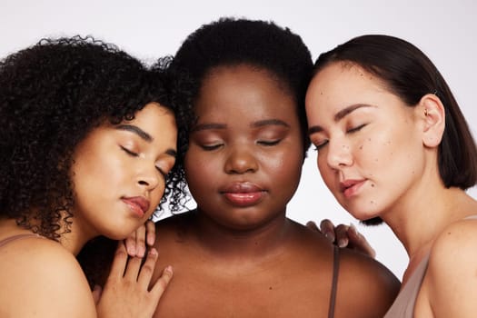 Women, diversity and studio with eyes closed for trust, support and inclusion with beauty aesthetic. Model, asian and black woman with cosmetics, makeup and wellness with skin health by background.